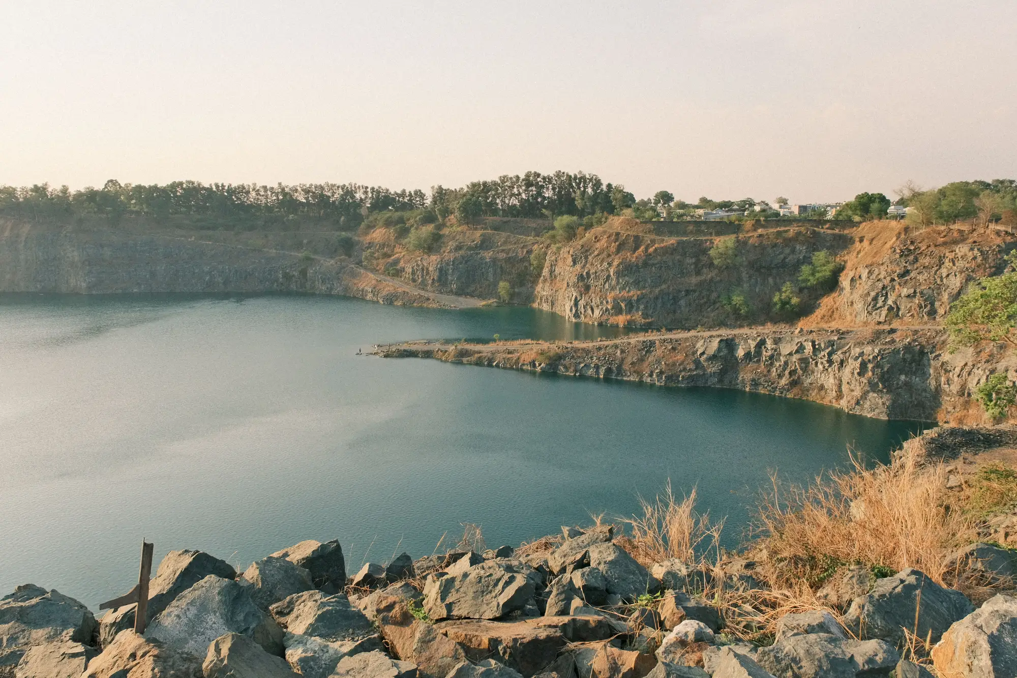 A quarry lake ringed by steep rock walls, with a narrow ledge of track along one side
